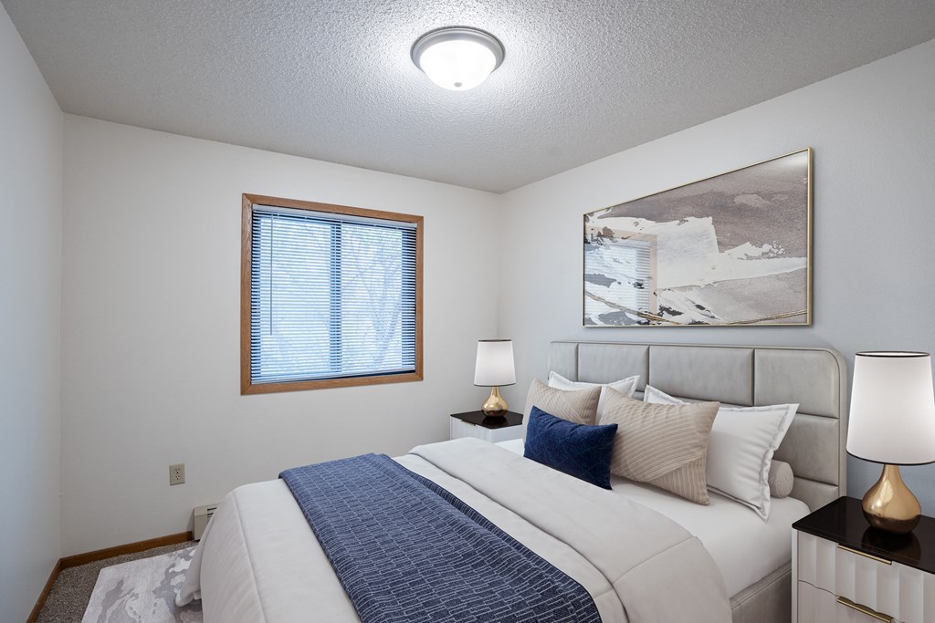 a bedroom with a large bed and a window. Fargo, ND Prairie Park Apartments