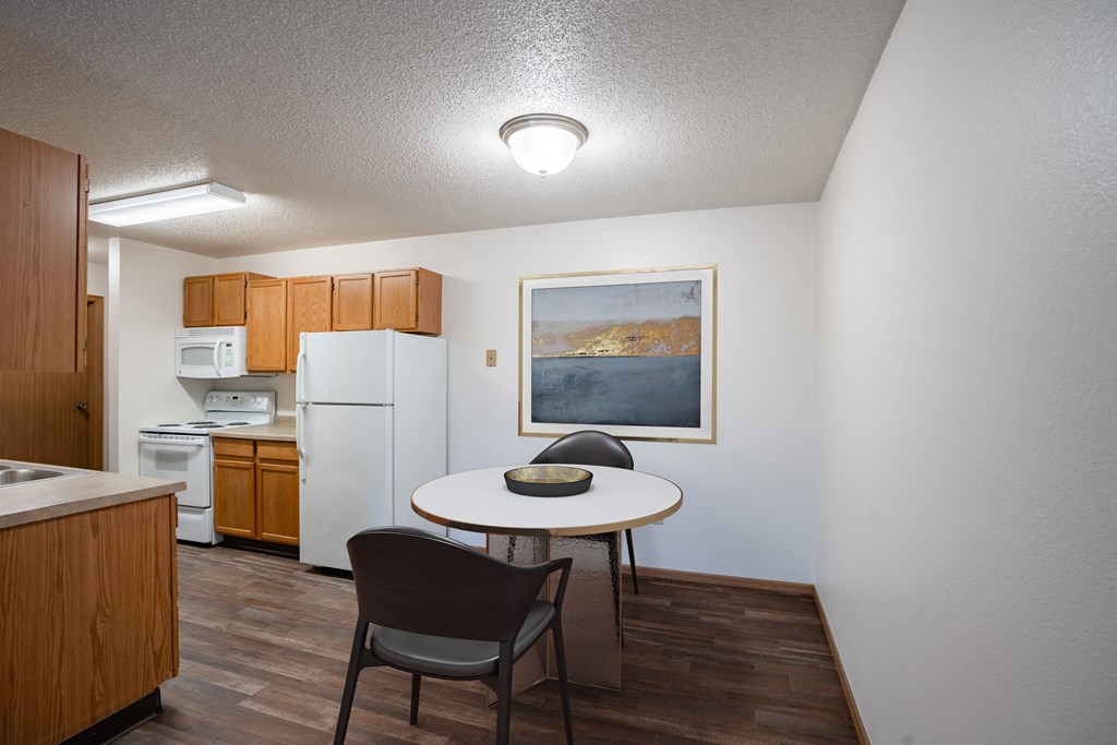 Fargo, ND Prairie Park Apartments | Dining a kitchen and dining area with a table and chairs and a refrigerator. Fargo, ND Prairie Park Apartments