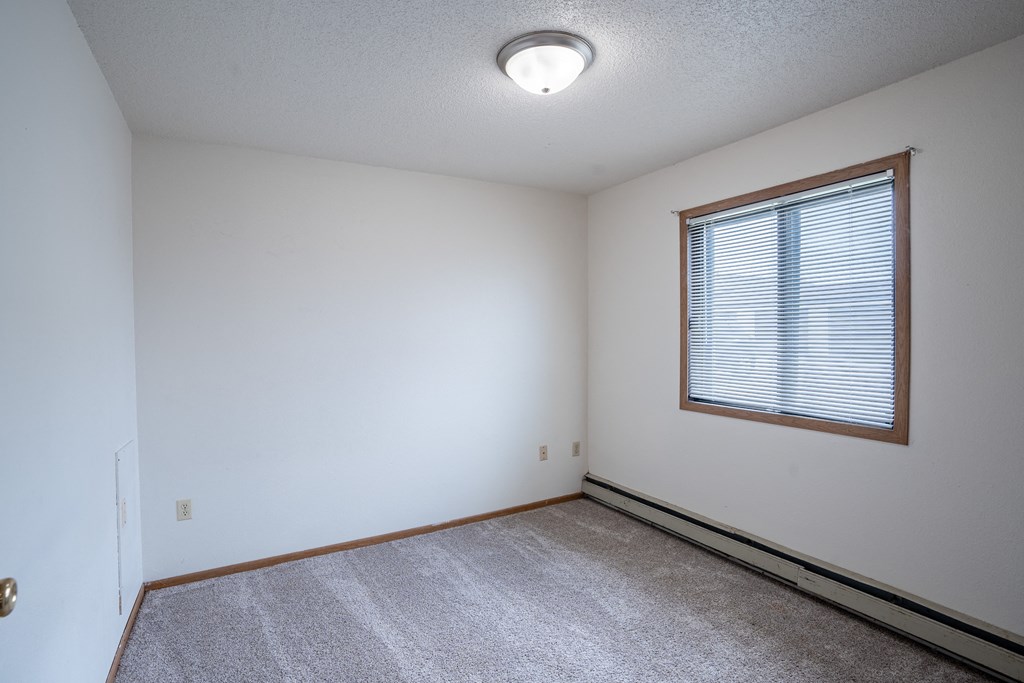 a bedroom with a large window and white walls. Fargo, ND  Prairie Park Apartments