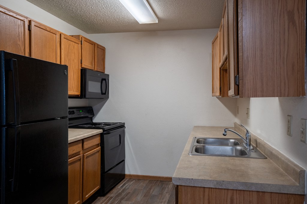 an empty kitchen with a sink and a refrigerator. Fargo, ND  Prairie Park Apartments