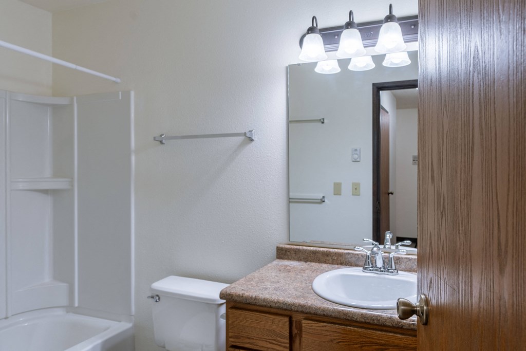a bathroom with a sink and a mirror and a shower. Fargo, ND Prairiewood Courts Apartments