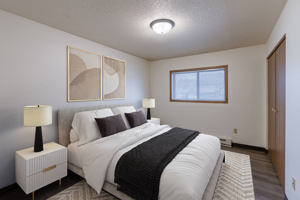 a bedroom with a large bed and a window. Fargo, ND Prairiewood Courts Apartments