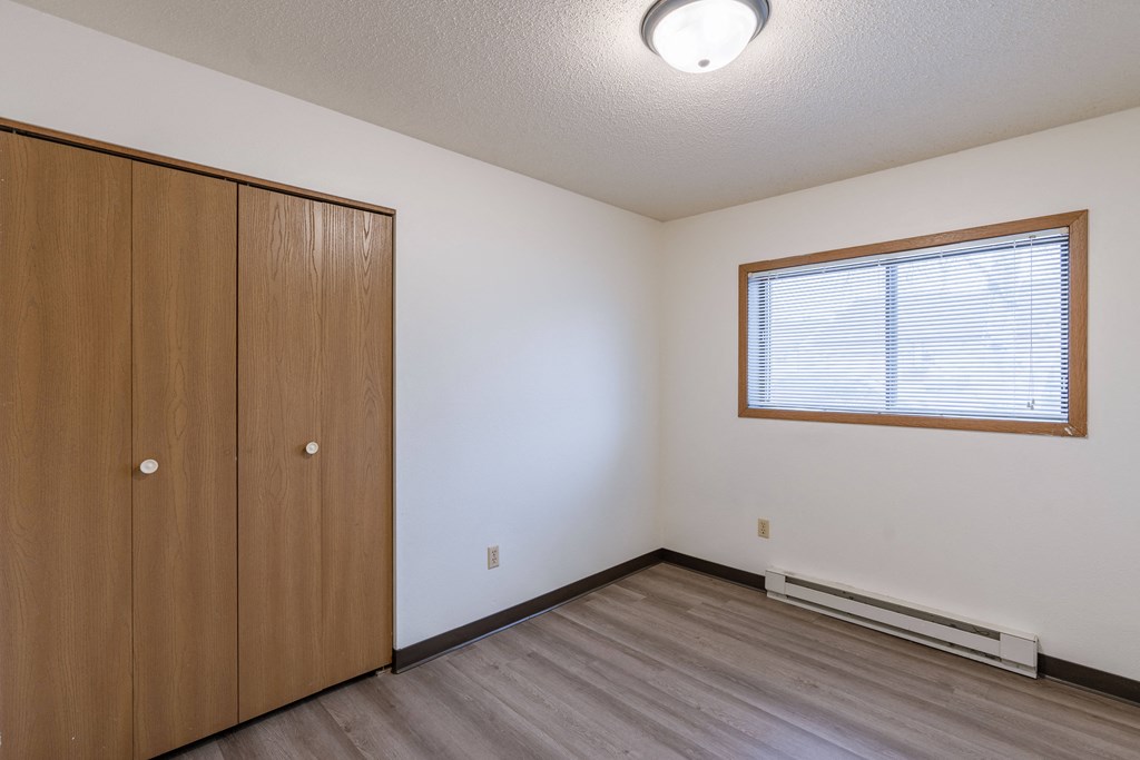 an empty bedroom with a closet and a window. Fargo, ND Prairiewood Courts Apartments