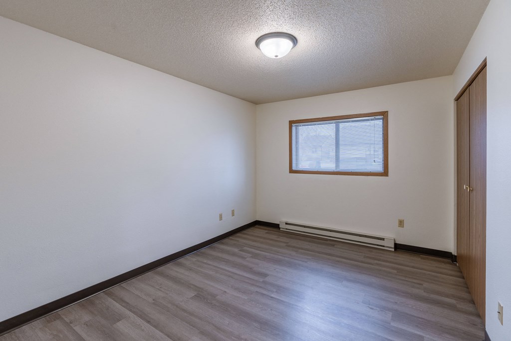 a bedroom with wooden floors and a window. Fargo, ND Prairiewood Courts Apartments