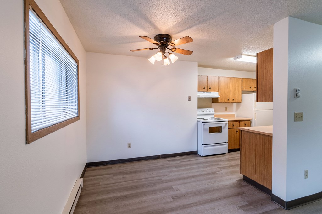 an empty kitchen with a ceiling fan and a window. Fargo, ND Prairiewood Courts Apartments