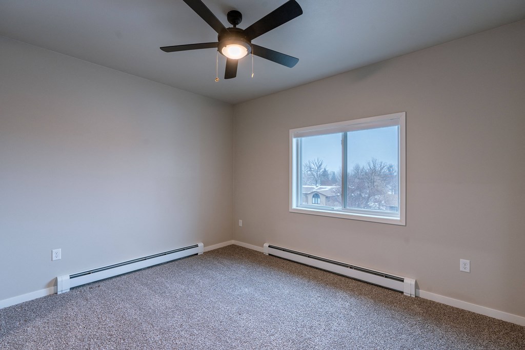 an empty room with a ceiling fan and a window. Fargo, ND Prairiewood Meadows Apartments
