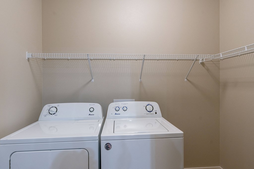 an empty laundry room with two washes and a dryer.Fargo, ND Prairiewood Meadows Apartments