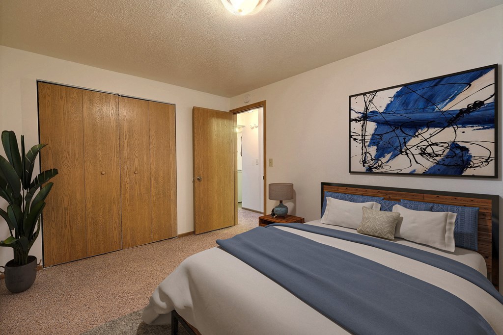 Fargo, ND Saddlebrook Apartments. a bedroom with a large bed and a potted plant