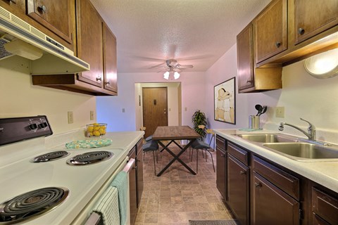 a kitchen with a stove and sink and a dining room with a table