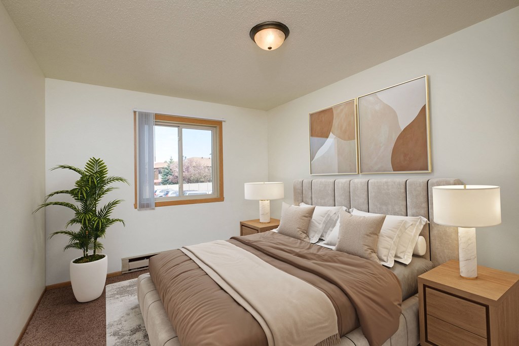 a bedroom with a large bed and a potted plant. Fargo, ND Sargent Apartments