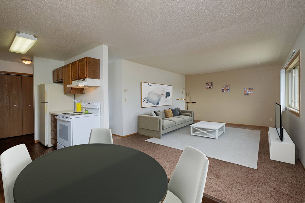 a living room and dining room with a black table and chairs and a white kitchen. Fargo, ND Sargent Apartments