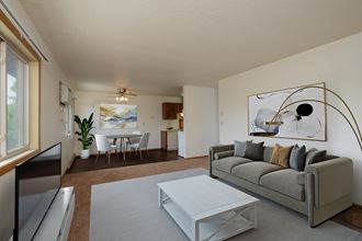 a living room with a couch and a coffee table and a dining room and kitchen. Fargo, ND Sargent Apartments