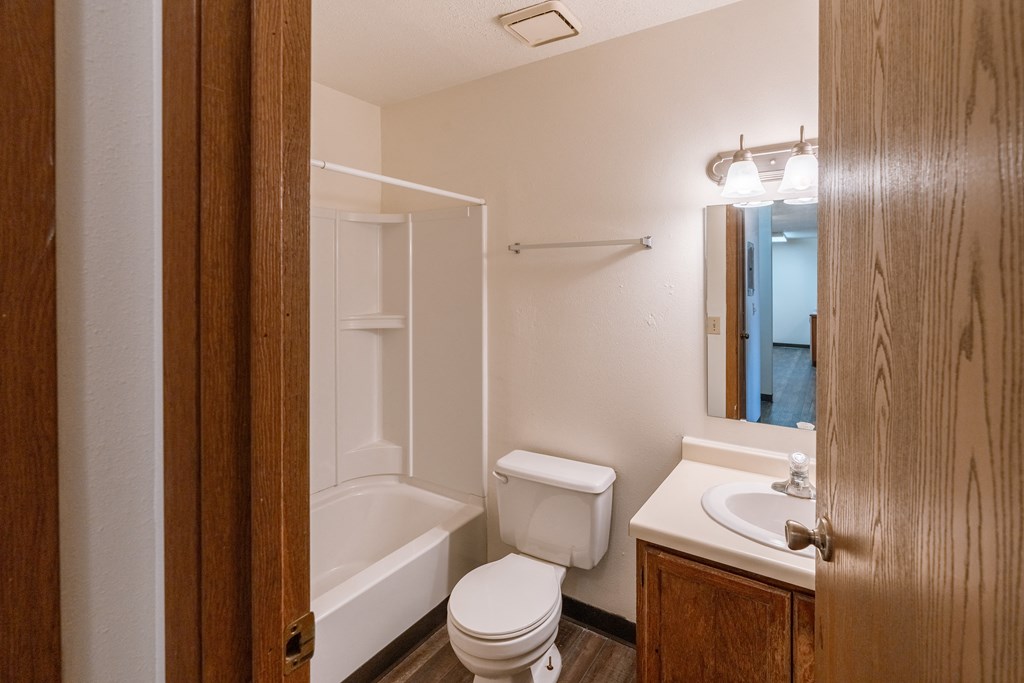 a bathroom with a toilet and a tub and a sink. Fargo, ND Sargent Apartments