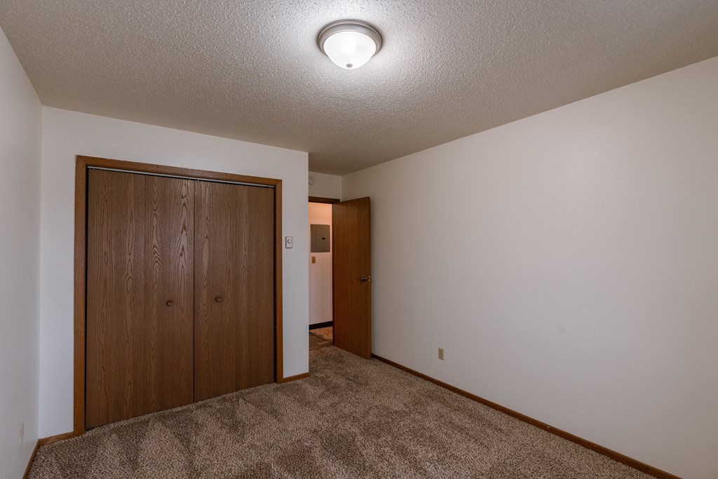 a bedroom with a closet and a door to a hallway. Fargo, ND Sargent Apartments