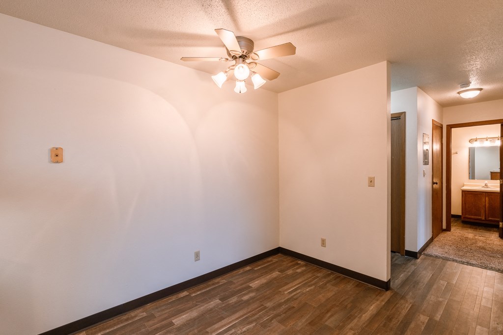 a living room with white walls and a ceiling fan. Fargo, ND Sargent Apartments