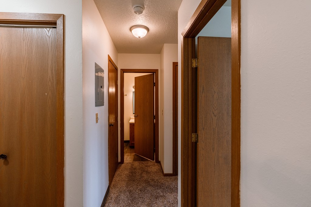 a hallway with two doors and a door to a bathroom. Fargo, ND Sargent Apartments.