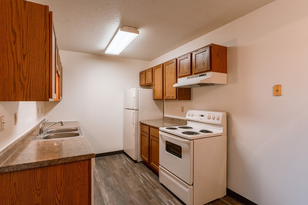 a kitchen with a stove refrigerator and sink. Fargo, ND Sargent Apartments