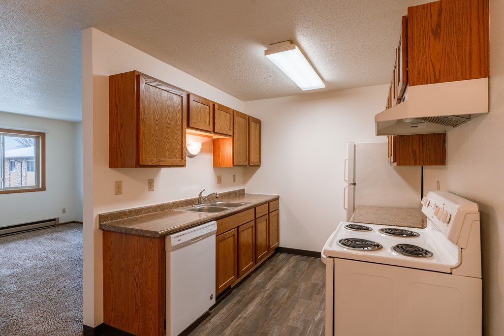 an empty kitchen with a stove refrigerator and sink. Fargo, ND Sargent Apartments