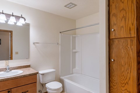 a bathroom with a shower toilet and sink and a mirror. Fargo, ND Schrock Apartments