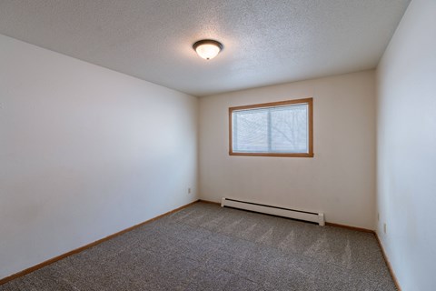 a bedroom with white walls and a window. Fargo, ND Schrock Apartments