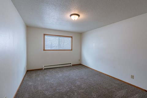 a bedroom with white walls and a window. Fargo, ND Schrock Apartments