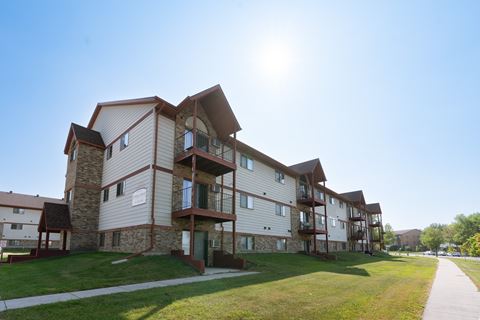 The exterior of an apartment with three levels and a sidewalk out front. Fargo, ND Sheridan Pointe Apartment.