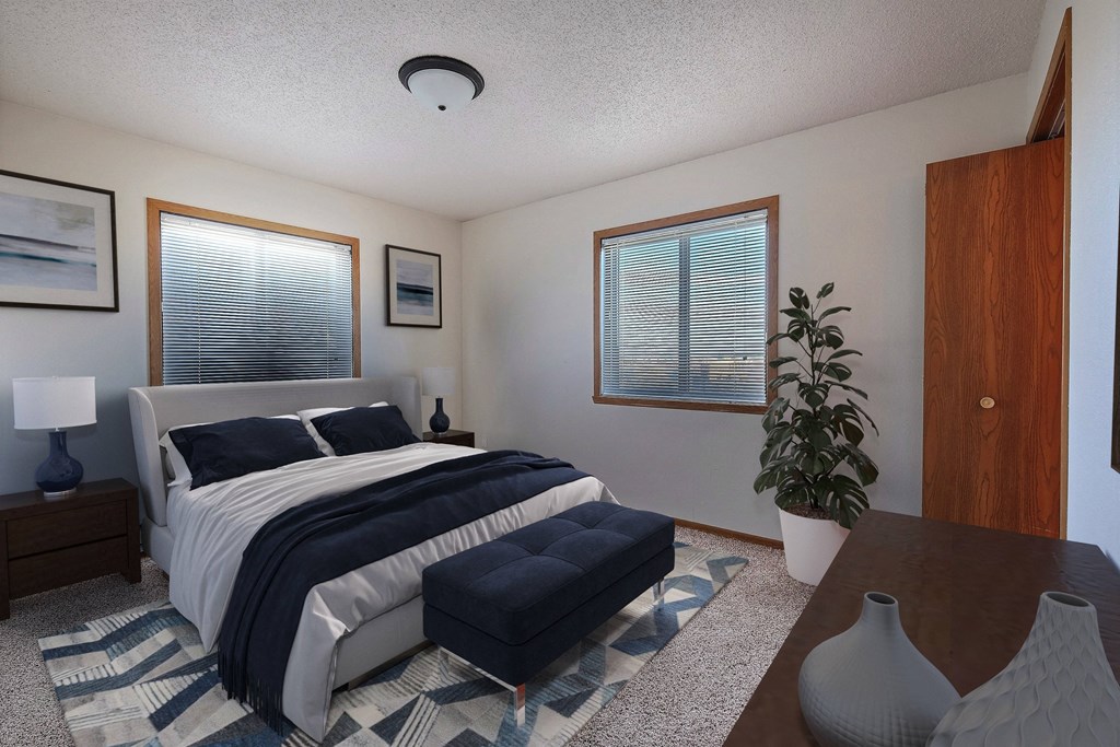 a bedroom with a bed and two windows. Fargo, ND Somerset Apartments