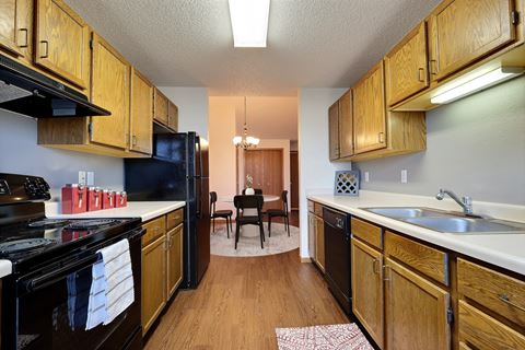 Fargo, ND Somerset Apartments. a kitchen with wooden cabinets and black appliances