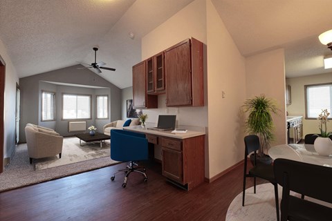 a desk with a laptop computer in a room with a couch and a table. Fargo, ND Somerset Apartments