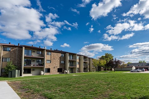 The exterior of a three level apartment building with a grass area out front. Fargo, ND South Pointe Apartments