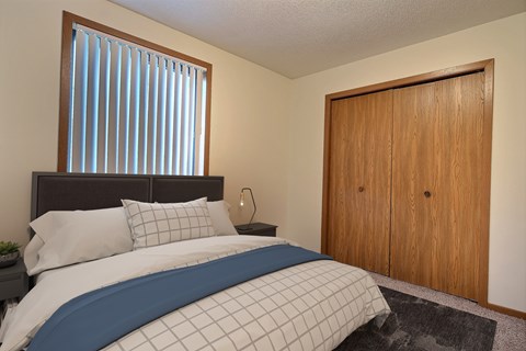 a bedroom with a bed and a closet. Fargo, ND Southgate Apartments