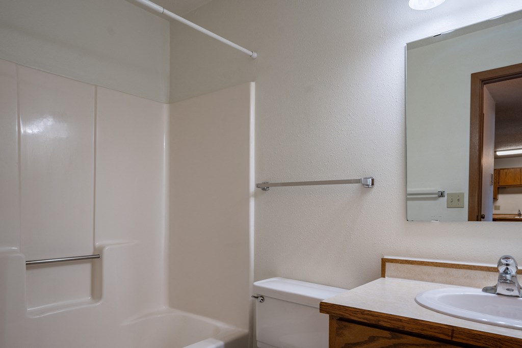 a bathroom with a sink and a shower and a mirror. Fargo, ND Southview Village Apartments