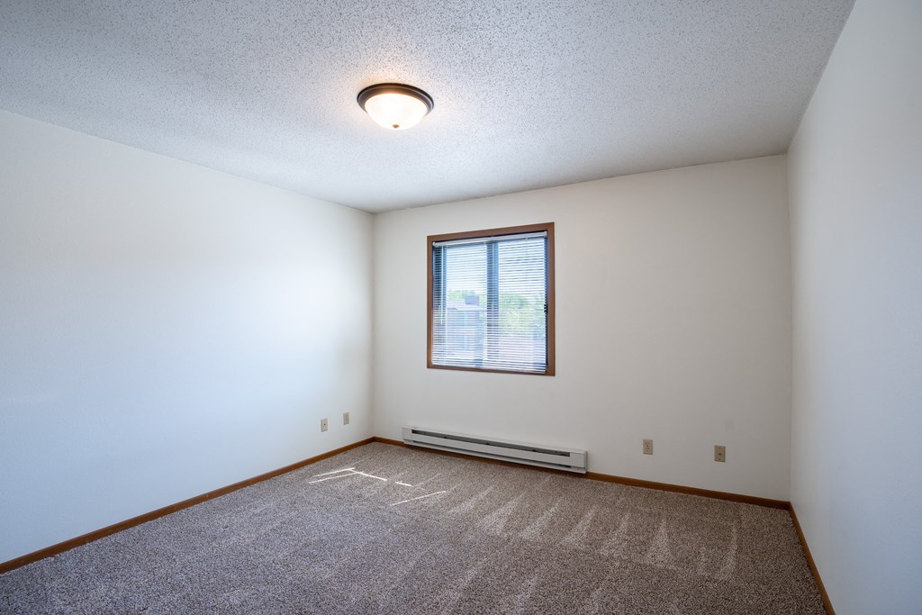 a bedroom with carpet and a window. Fargo, ND Southview Village Apartments