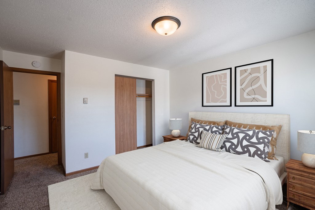a bedroom with a large bed and a closet. Fargo, ND Southview Village Apartments