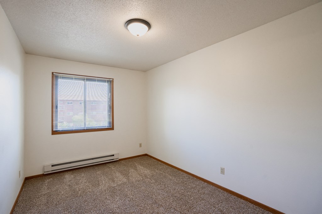 a bedroom with carpet and a window. Fargo, ND Southview Village Apartments