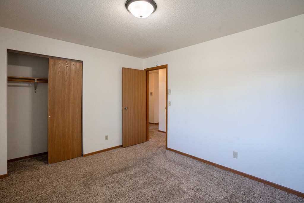 a bedroom with carpet and a door to a closet. Fargo, ND Southview Village Apartments
