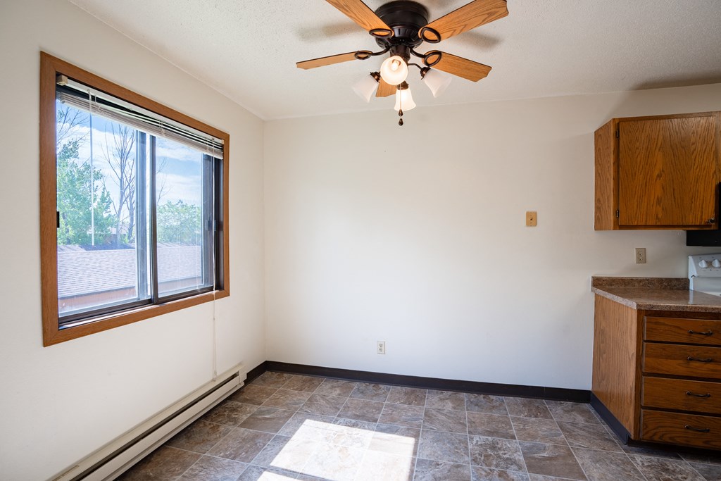 an empty kitchen with a ceiling fan and a window. Fargo, ND Southview Village Apartments