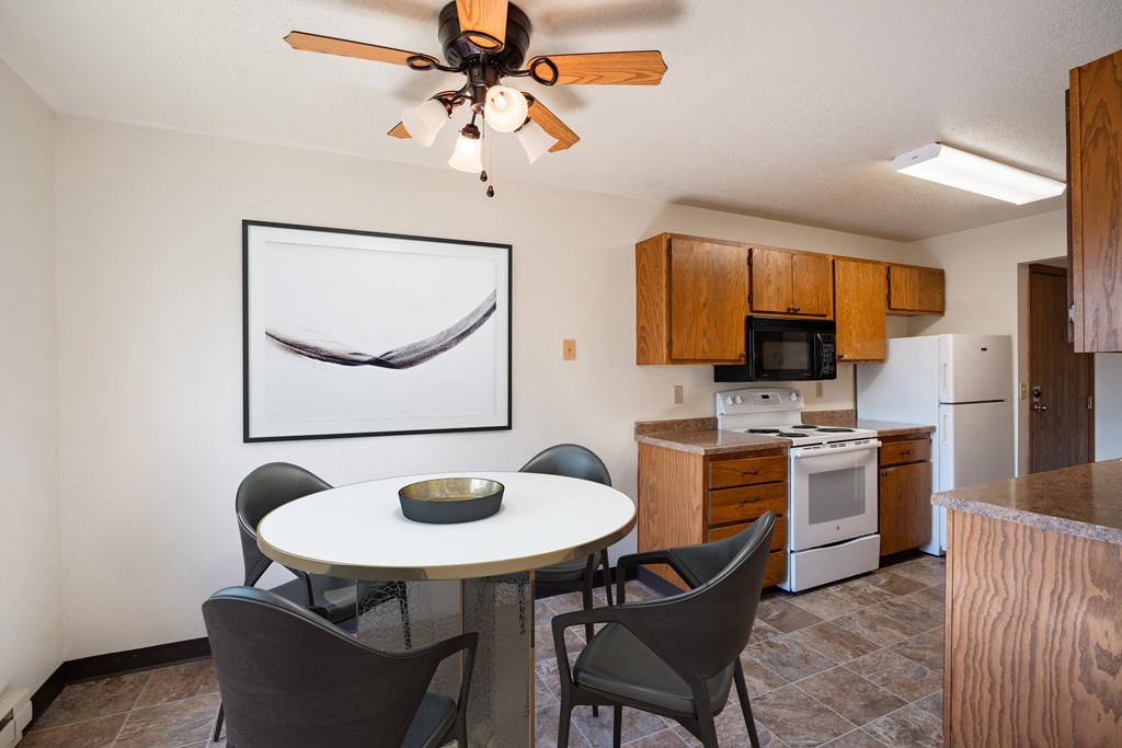 a kitchen and dining area with a table and chairs and a ceiling fan. Fargo, ND Southview Village Apartments