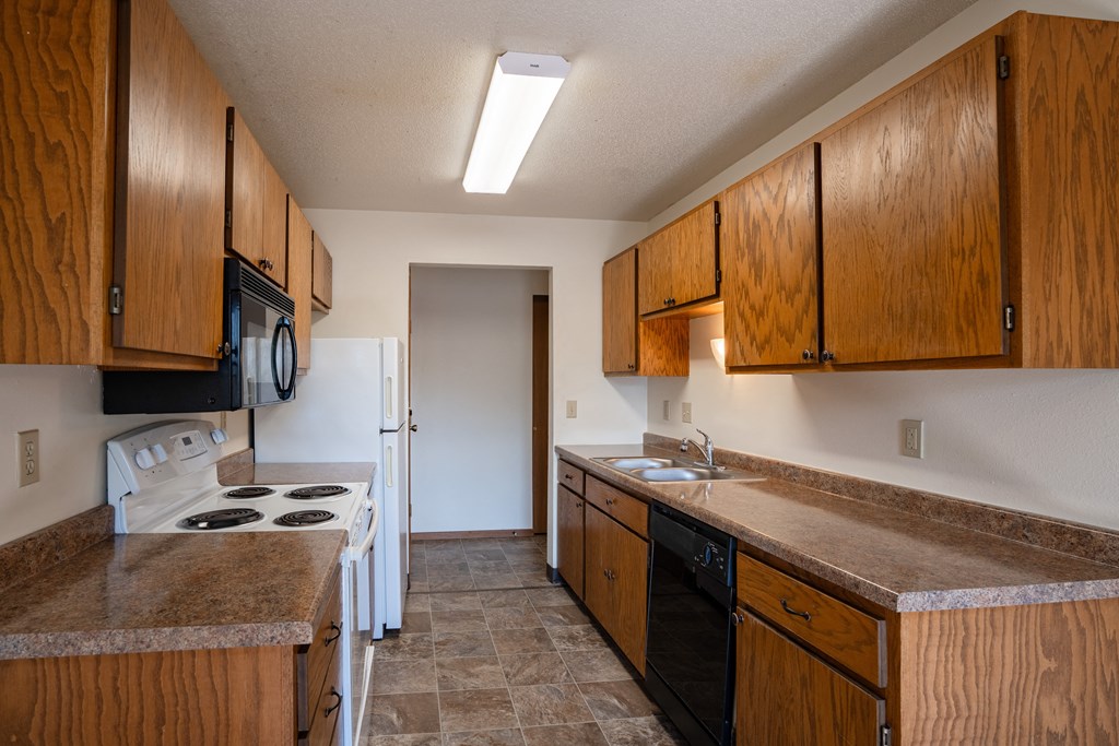 a kitchen with wooden cabinets and a stove and a sink. Fargo, ND Southview Village Apartments