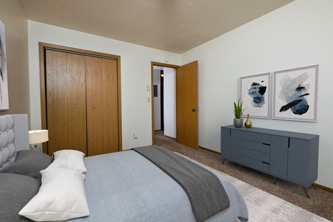 a bedroom with a closet, bed, and dresser. Fargo, ND Southwind Apartments