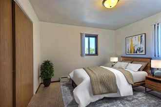 a bedroom with a bed and a potted plant. Fargo, ND Spring Apartments