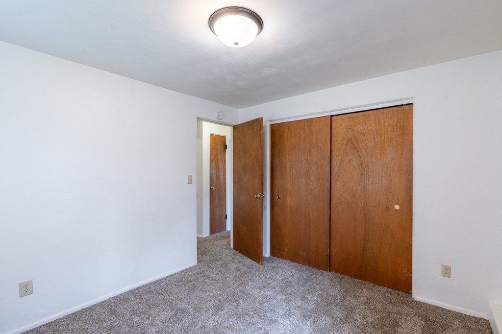 a bedroom with white walls and wooden doors and a ceiling light. Fargo, ND Spring Apartments