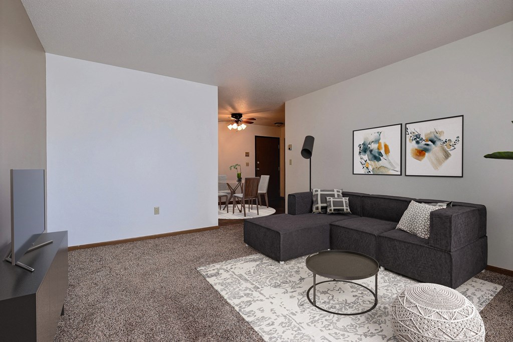 an empty living room with a couch and a tv. Fargo, ND Sterling Park Apartments