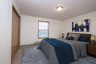 a bedroom with a bed and a door to a bathroom. Fargo, ND Stonebridge Apartments
