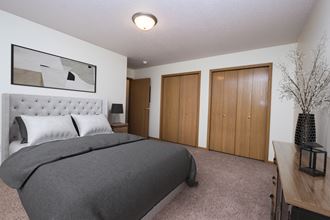 a bedroom with a bed and two closet doors. Fargo, ND Stonebridge Apartments