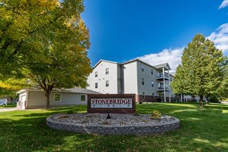 An exterior of an apartment with a sign and underground garage out front.  Fargo, ND Stonebridge Apartments.