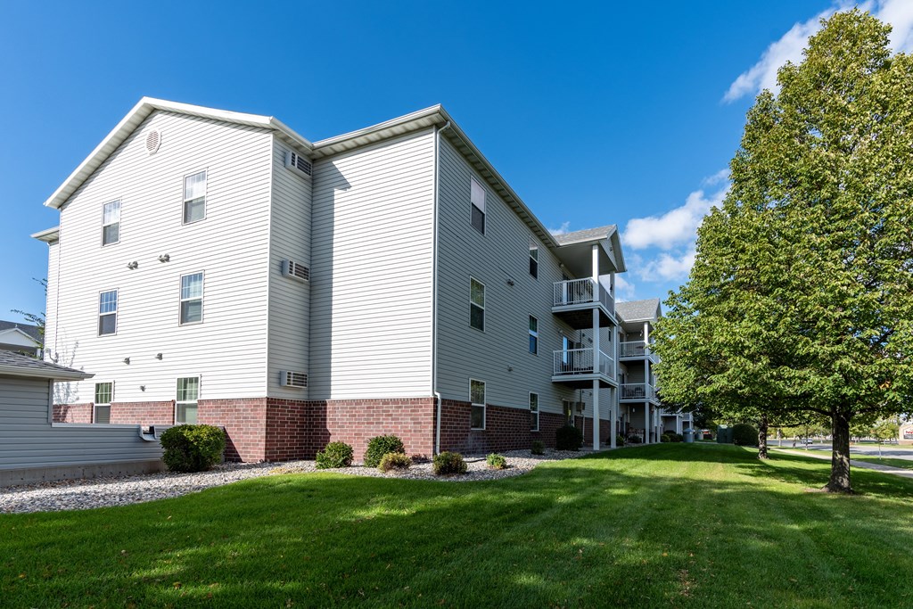 An exterior of an apartment with a grassy area out front.
