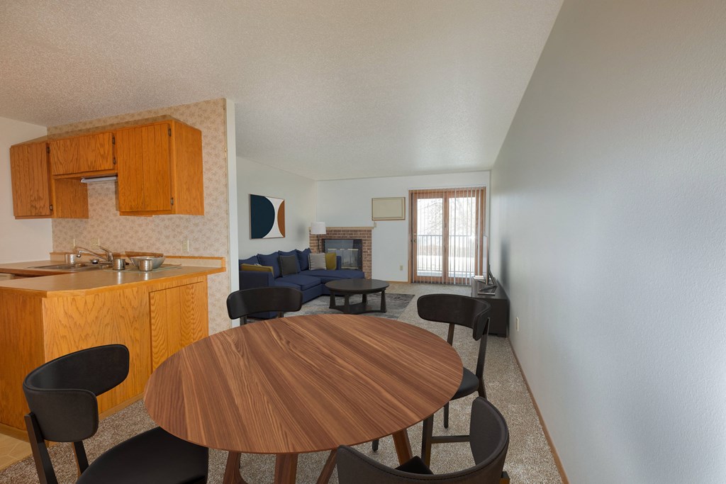 a dining area with a table and chairs and a living room with a couch and a fireplace