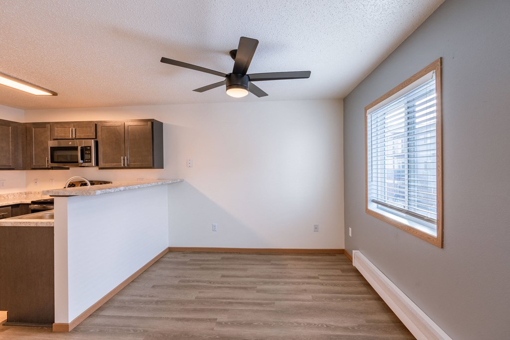 an empty kitchen with a ceiling fan and a window. Fargo, ND Sunwood Apartments