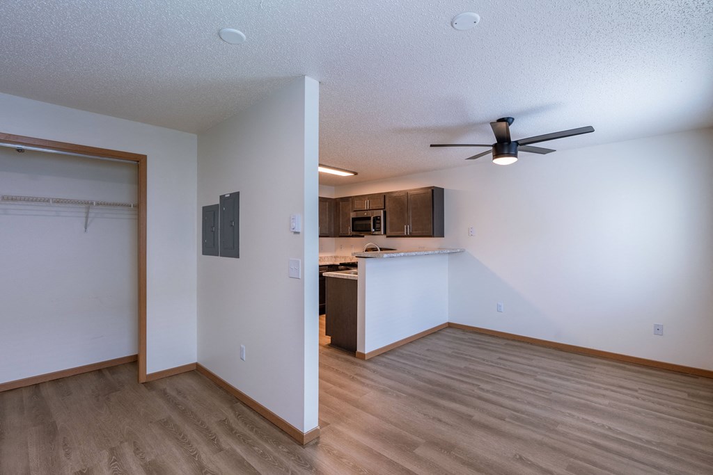 an empty living room and kitchen with a ceiling fan. Fargo, ND Sunwood Apartments